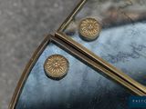 a pair of gold buttons sitting on top of a mirror