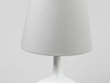 une lampe de table blanche surmontée d'un abat-jour gris
