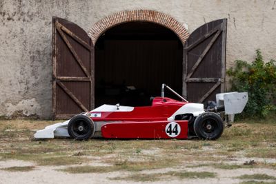une voiture de course rouge et blanche garée devant un immeuble