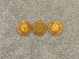 three gold coins, one of which is a sovereign and one of which is a sovereign