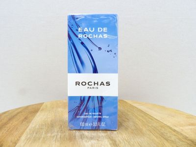 un flacon de parfum Rochas posé sur une table en bois