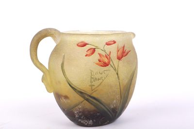 a glass pitcher with flowers painted on it on a white surface