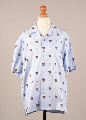 La chemise est bleue et est ornée d'un motif de tasses à café.