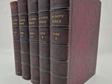 three old books are lined up on a white surface