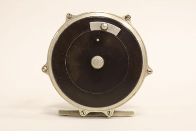 a black and silver clock on a stand on a white surface
