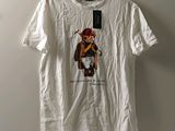 un t-shirt blanc avec un ours Polo dessiné dessus