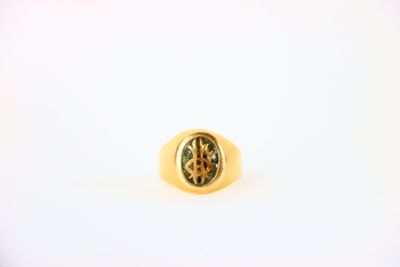 Gros plan sur une bague en or ornée d'une pierre verte
