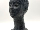 sculpture représentant une tête de femme posée sur un socle, sur fond blanc