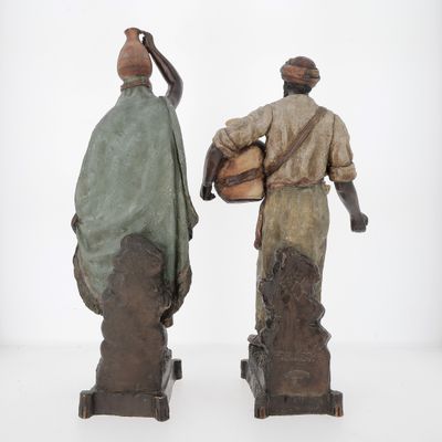 deux statues représentant un homme et une femme portant des paniers sur le dos