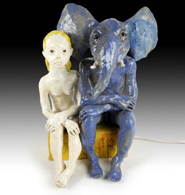 une figurine représentant un homme assis sur une chaise à côté d'un éléphant