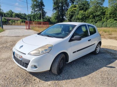 une petite voiture blanche garée sur un parking en gravier