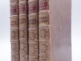quatre vieux livres sont empilés les uns sur les autres sur une surface blanche