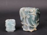 two pieces of carved jade on a black surface