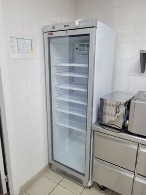 un réfrigérateur ouvert dans une cuisine où se trouve un micro-ondes posé sur le plan de travail