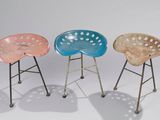 trois tabourets en plastique de couleurs différentes, placés les uns à côté des autres sur une surface blanche