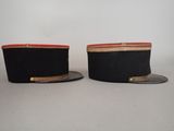 pair of black hats with red trims on top of each other