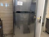 a stainless steel refrigerator in a kitchen with tile flooring