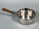 an old silver saucepan with a wooden handle on a white surface