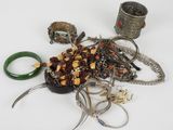 un tas de bijoux posés sur une surface blanche, avec des ciseaux