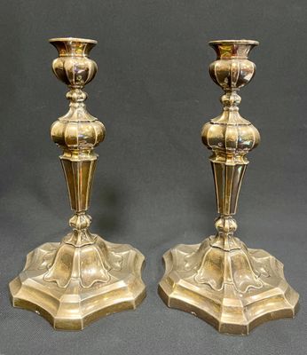 pair of antique brass candlesticks on pedestals on a gray background