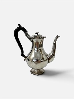 une théière ancienne en argent, avec une anse noire sur fond blanc
