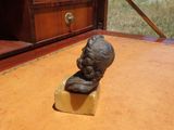une petite statue représentant un homme assis sur une table en bois