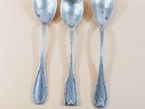 three silver spoons and two silver spoons on a white surface