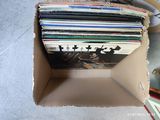 une boîte en carton remplie de disques, posée par terre