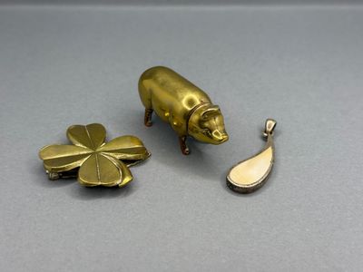 breloques en forme de cochon en laiton et de trèfle à quatre feuilles sur un fond gris