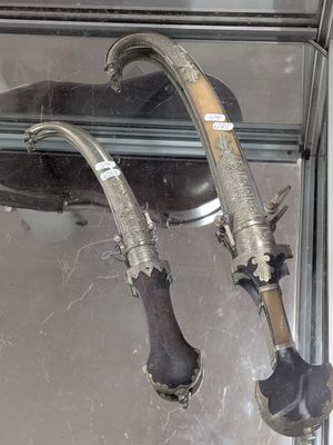 deux paires de couteaux argentés et noirs dans un coffret en verre