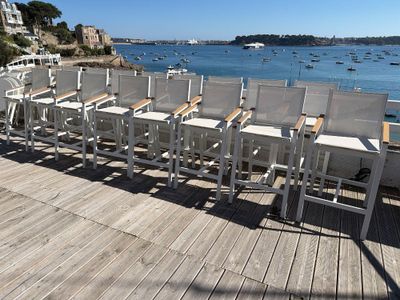 a lot of white chairs sitting on a wooden deck by the water