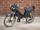 a black motorcycle that is parked in front of a brick wall