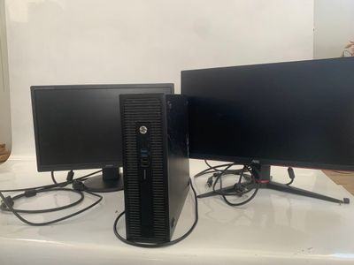two computer monitors sitting on top of a table next to each other