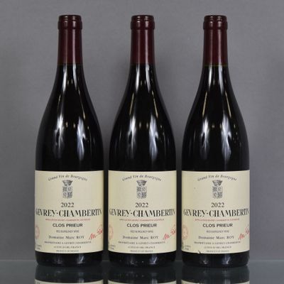 three bottles of wine sit on a glass table in front of a gray background