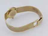 a close up of a gold watch on a white surface