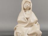 une statue blanche représentant une femme assise par terre
