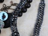 a black necklace with beads and a button on it