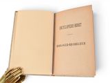 an open book with a gold glove on top of it