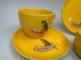 a yellow cup and saucer with a green parrot on it