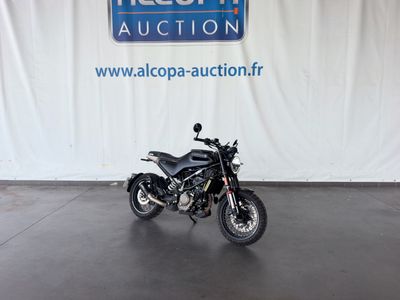 une moto garée devant une grande banderole blanche sur laquelle figure un logo