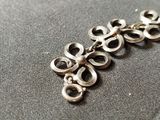 a close up of a silver necklace on a table