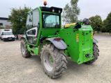 a green tractor parked in a parking lot next to a white truck