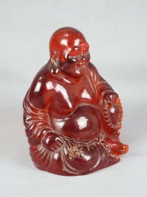 une image représentant une petite statuette de Bouddha rouge posée sur une surface blanche
