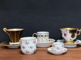 five cups and saucers sitting on a wooden table
