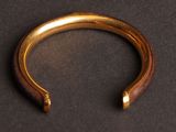 a close up of a gold bracelet on a black surface