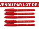 quatre stylos rouges empilés les uns sur les autres sur une surface blanche