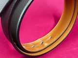 a close up of a black leather belt on a pink background