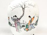 un vase blanc avec un tableau posé sur une table