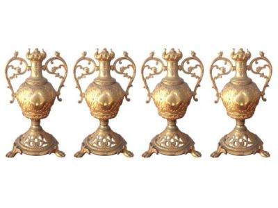quatre vases en laiton vieilli sont alignés sur un fond blanc