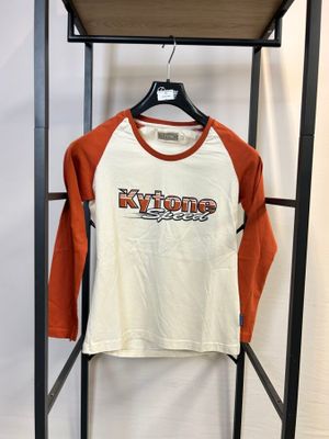 un t-shirt à manches longues orange et blanc suspendu à un portant